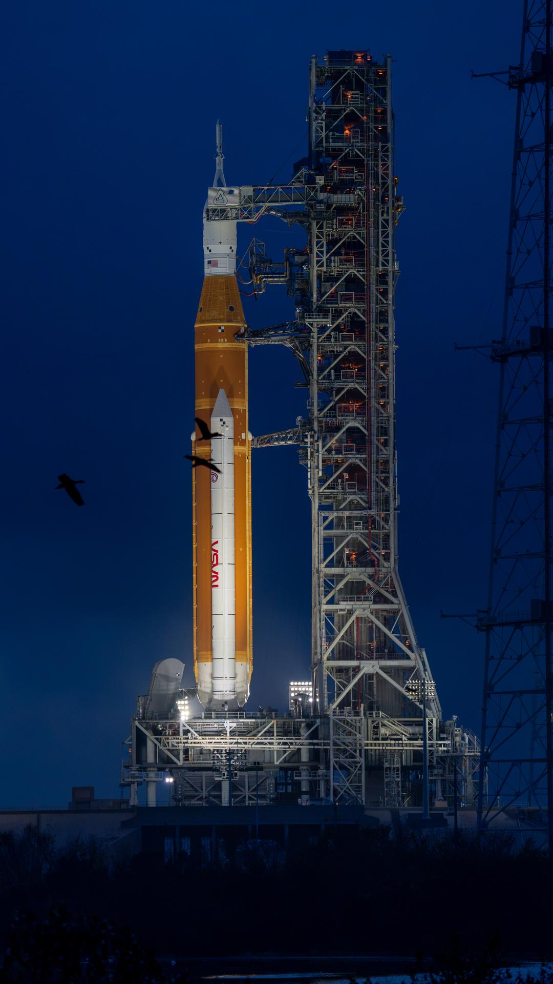 This image shows a sunset of NASA’s SLS (Space Launch System) and Orion spacecraft at NASA’s Kennedy Space Center. NASA's massive Crawler-Transporter, upgraded for the Artemis program, carried the powerful SLS rocket and Orion spacecraft on the Mobile Launcher from the Vehicle Assembly Building to Launch Pad 39B at Kennedy Space Center in preparation for the Artemis II mission.